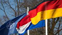 Flaggen aus dem I. Deutsch-Niederländisches Corps in Bergen Eine NATO-Flagge, die niederländische und die deutsche Nationalflagge wehen im Wind.