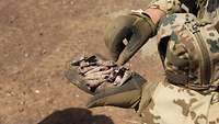 Ein deutscher Soldat hält Munitionsüberreste in der Hand.