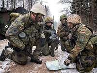 Soldaten knien auf dem Waldboden über einer Karte.