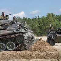 Ein Pionierpanzer schiebt mit seinem vorn angebrachten Räumschild Erdmasse vor sich her.