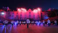 Nächtlicher Showauftritt vor historischer Kulisse. Feuerwerk. Publikum seitlich auf Tribünen.