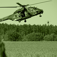 Ein Hubschrauber schwebt dicht über einem Feld.