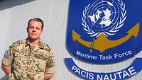 Boris M. steht neben dem Wappen der Maritim Task Force