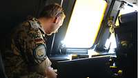 Soldat sitzt im Cockpit und schaut auf seinen Laptop