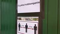 Auf der Tür zum Eingang des Sanitärhauses weist ein Schild auf die Einhaltung des Mindestabstandes hin.