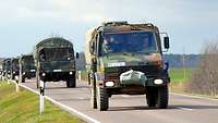 Lastkraftwagen der Bundeswehr fahren auf einer Straße hinter einander.