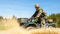 Soldat fährt mit Quad durch Pfütze