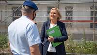 Dr. Eva Högl steht mit dem Infrastrukturbeauftragten vor einem im Bau befindlichen Gebäude